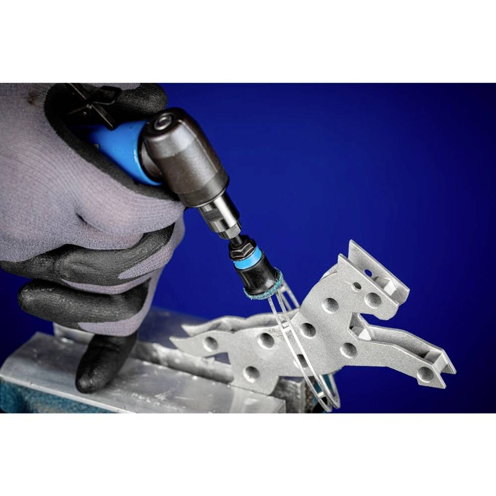 Una persona con un guanto tiene un trapano metallico che lavora un pezzo di metallo a forma di cavallo. Lo sfondo è blu.