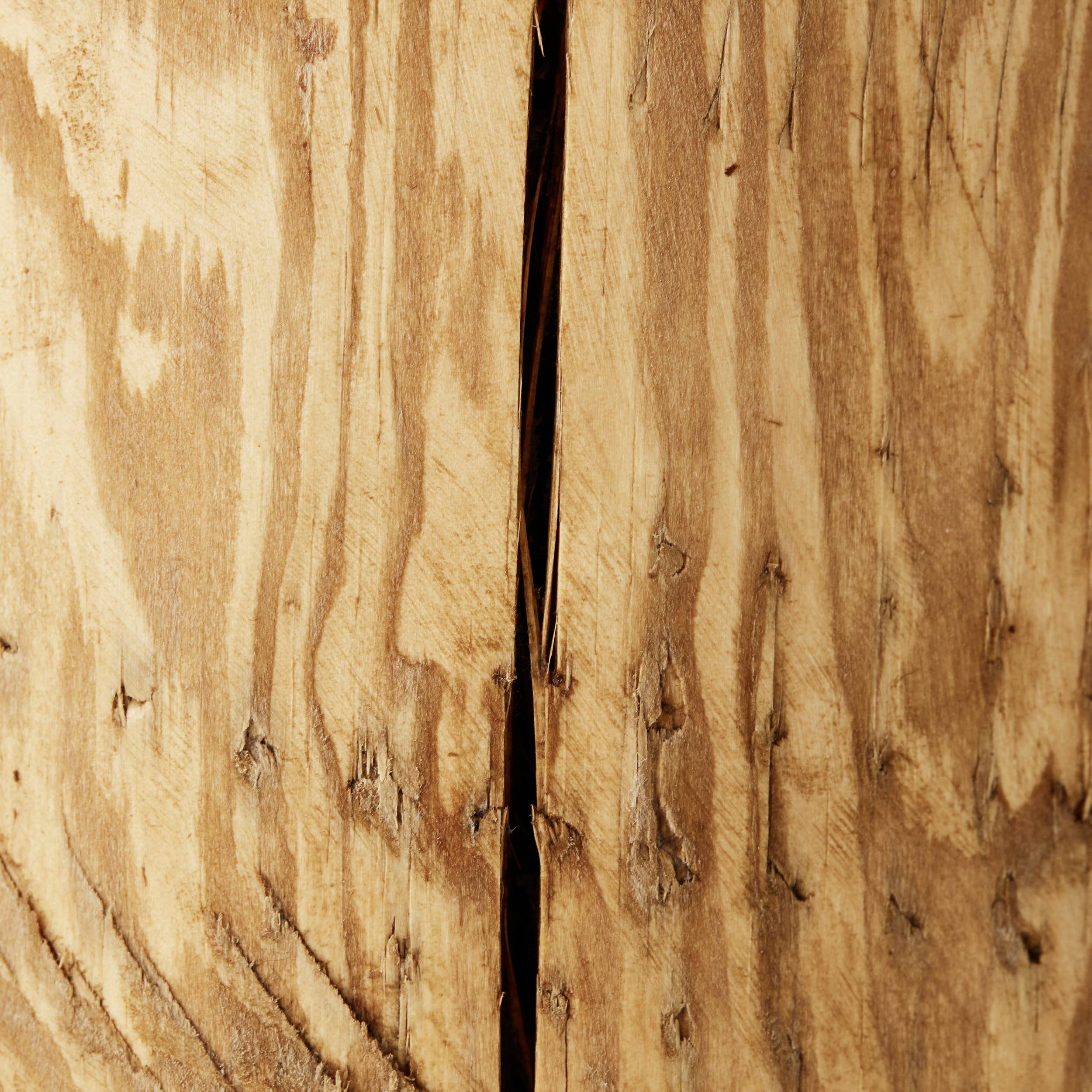 Superficie di legno con venatura naturale e una crepa verticale al centro. La texture appare ruvida e mostra evidenti segni di usura.
