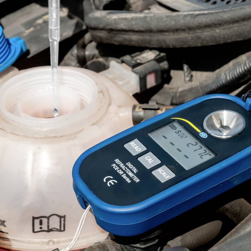 Un rifrattometro digitale misura la concentrazione di un liquido in un contenitore nel vano motore di un'automobile.
