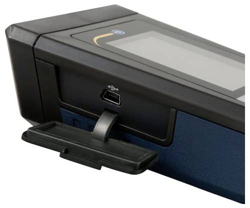 Primo piano di un dispositivo elettronico nero con una porta USB e un piccolo vassoio o coperchio sulla parte anteriore, mostrato su uno sfondo bianco.