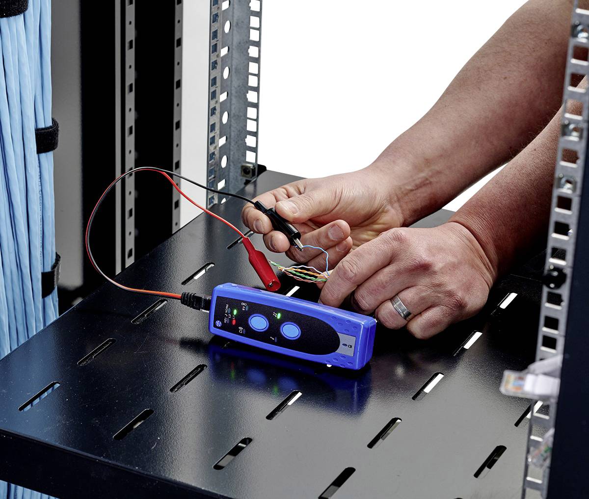 Una persona sta testando cavi in un rack server con un tester di cavi blu. Le mani tengono il tester e le estremità dei cavi.