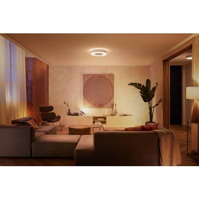 Soggiorno con illuminazione soffusa, arredato con mobili moderni, un grande divano, piante e un'opera d'arte appesa alla parete. Un'atmosfera accogliente.