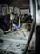 Una persona sta pulendo l'interno di un'auto senza sedili utilizzando un aspirapolvere. Indossa una mascherina protettiva e dei guanti.