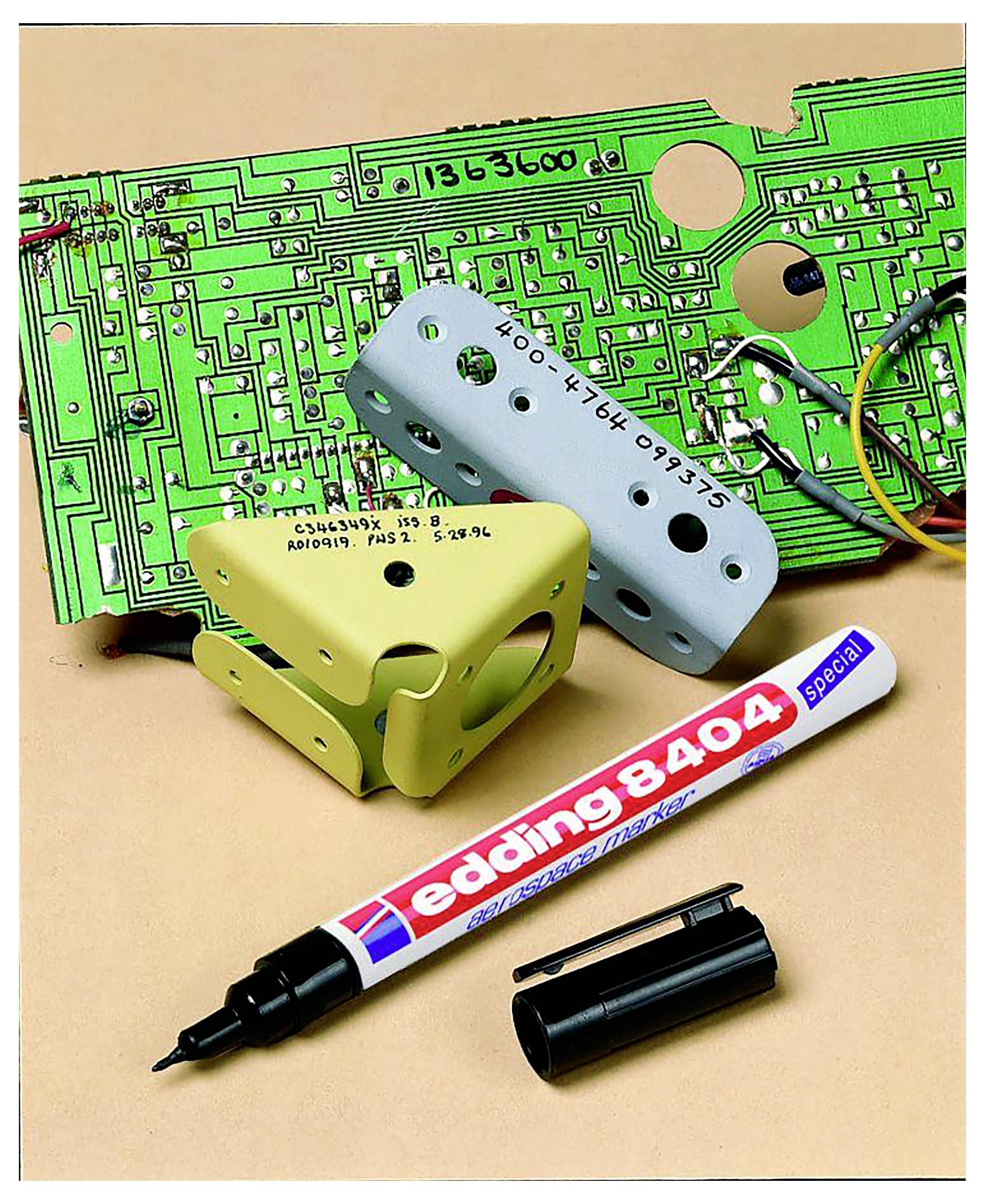 Due parti di plastica marcate, una scheda circuitale verde e un pennarello speciale Edding 8404 con tappo su una superficie beige.