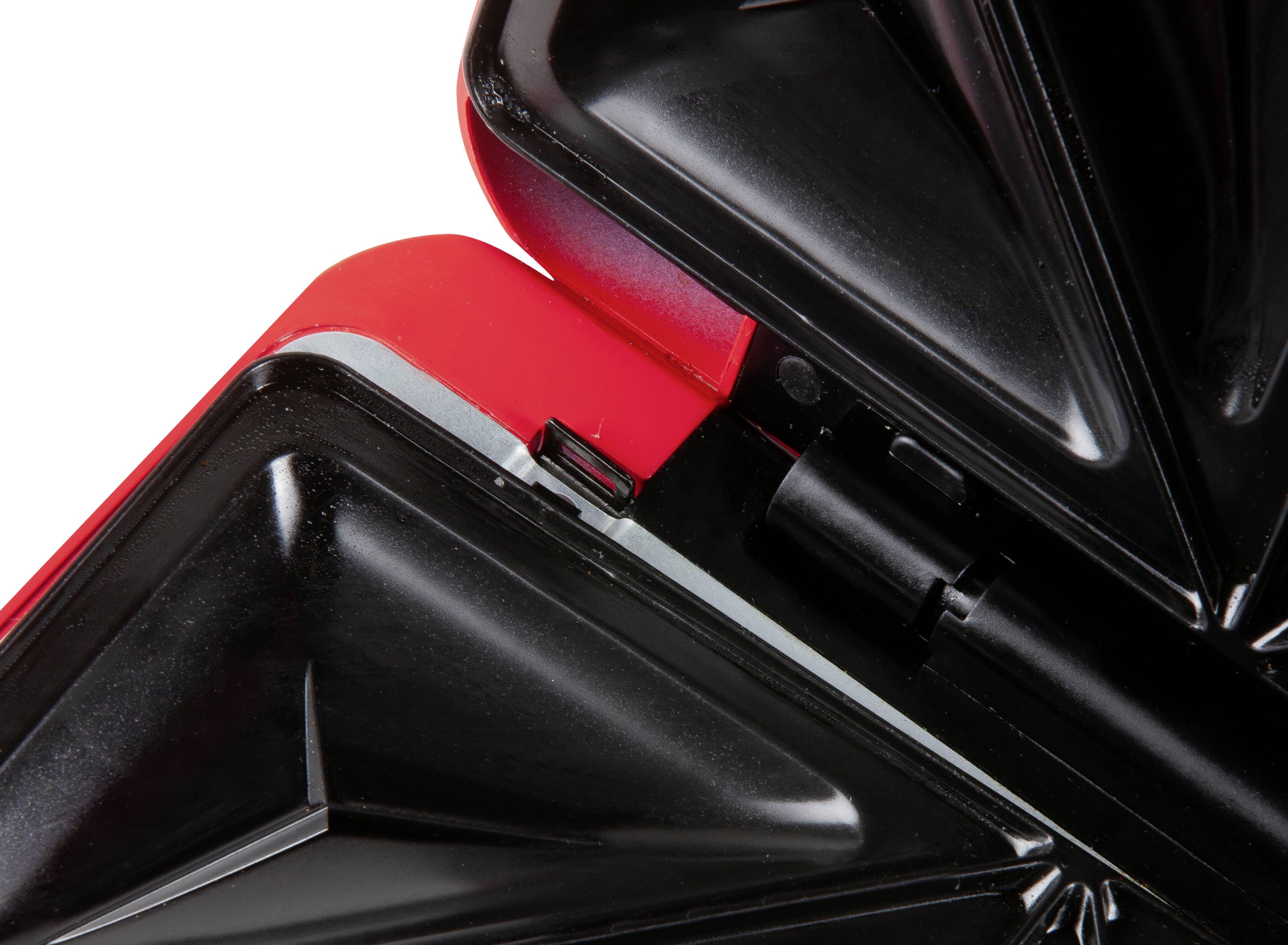 Primo piano di un sandwich maker con piastra riscaldante triangolare aperta. L'apparecchio è nero con un bordo rosso.