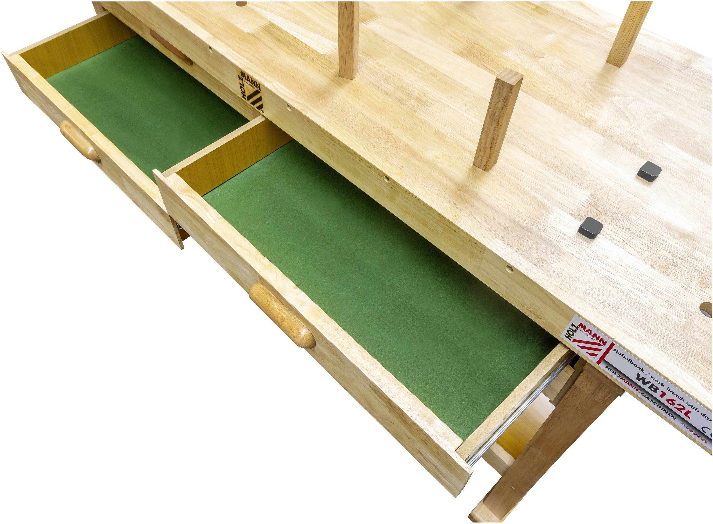 Tavolo in legno con cassetti di velluto verde estratti. Le gambe del tavolo sono rivolte verso l'alto. Sul retro è visibile un metro a nastro.