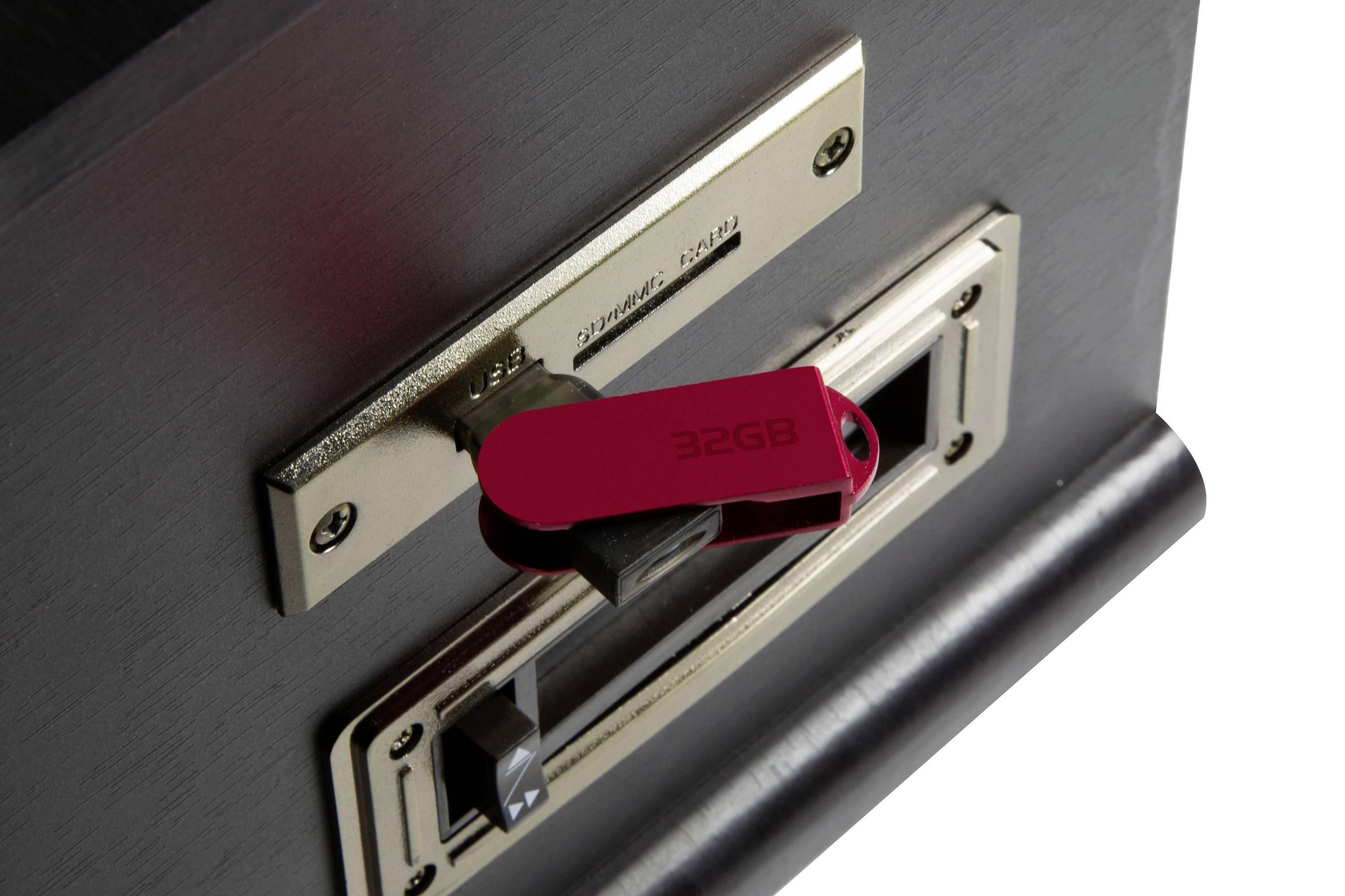 Una chiavetta USB rossa con la scritta '32GB' è inserita in un lettore di schede dall'aspetto antico.