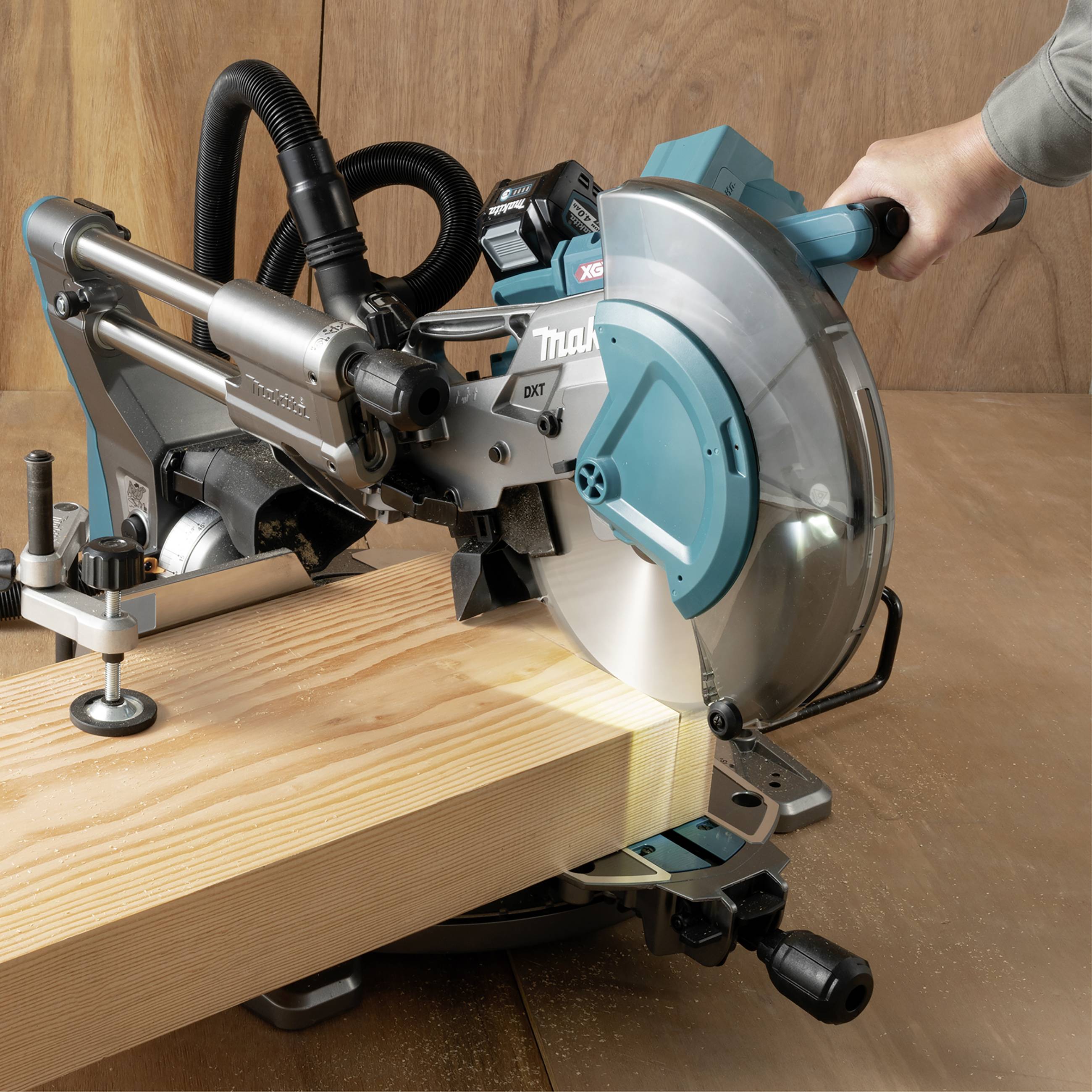 Una sega circolare taglia una tavola di legno. La sega viene guidata manualmente ed è posizionata davanti a uno sfondo di legno.