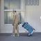 Una persona in abiti da lavoro sta trascinando un carrello blu per il trasporto con cassette degli attrezzi davanti a un edificio.