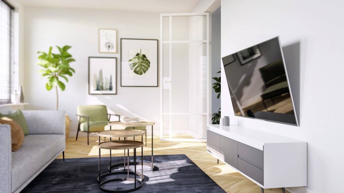 Soggiorno luminoso con mobili moderni, poltrona verde, arte parietale e grande televisore a schermo piatto sulla parete destra.