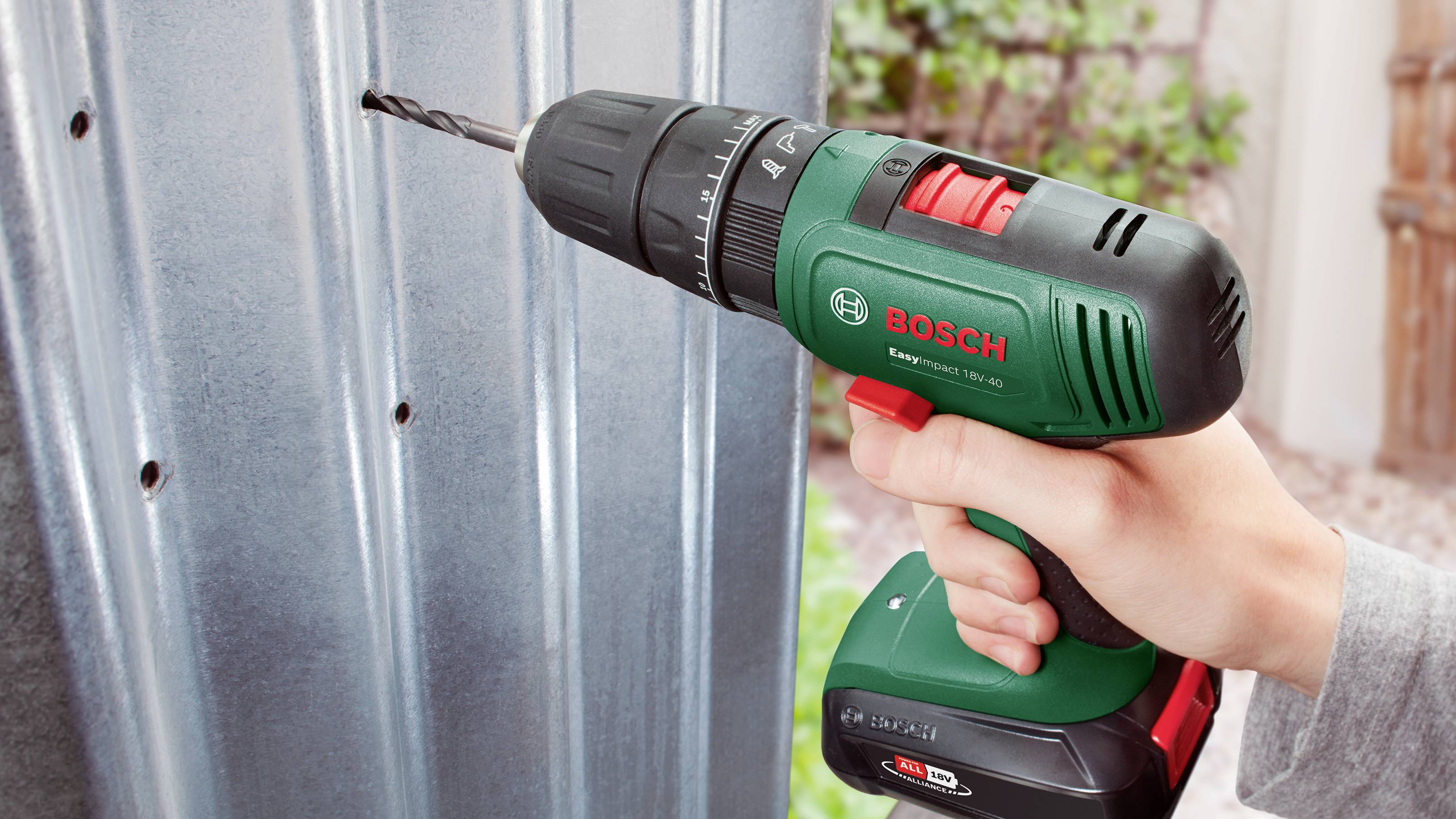 Una mano impugna un avvitatore a batteria Bosch e perfora un lamierino metallico.