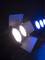 Due fari da palcoscenico illuminano un ambiente buio, uno con luce bianca e l'altro con luce blu.