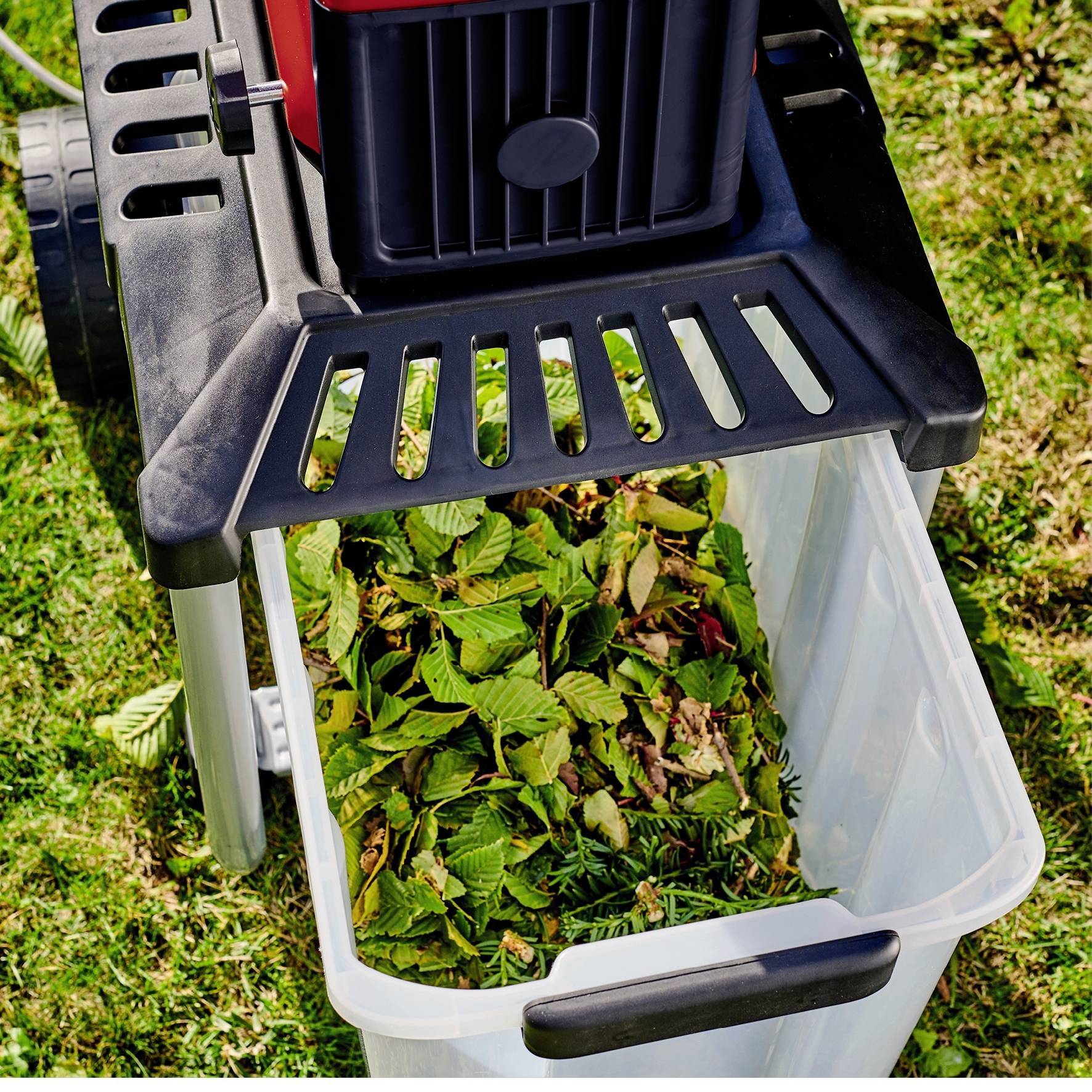 Un tritarami elettrico per giardino tritura rami e foglie. Il contenitore di raccolta è metà pieno di materiale tritato.