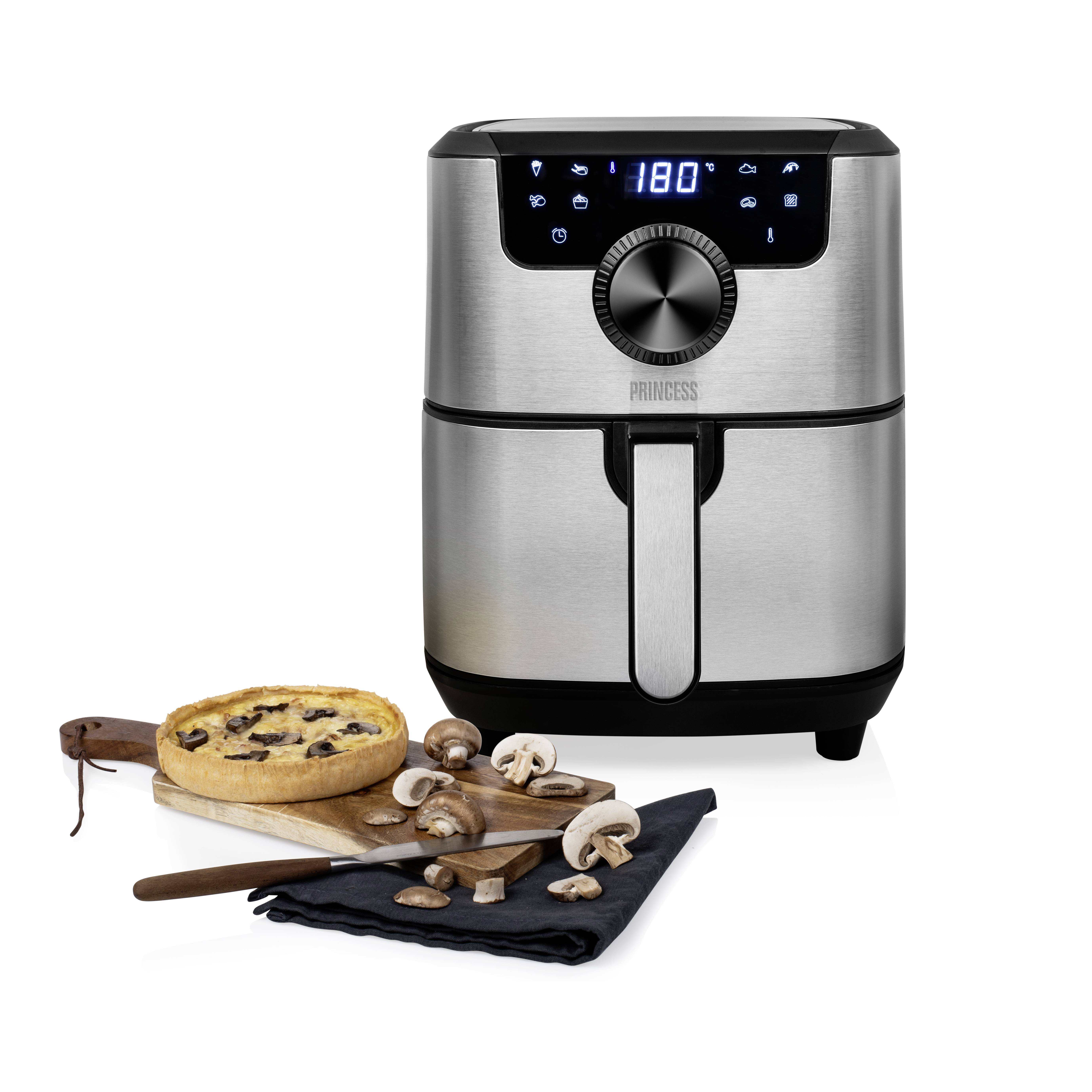 Friggitrice ad aria calda argentata con display digitale che mostra '180°'. Accanto, un quiche ai funghi, funghi freschi e posate su un tagliere.