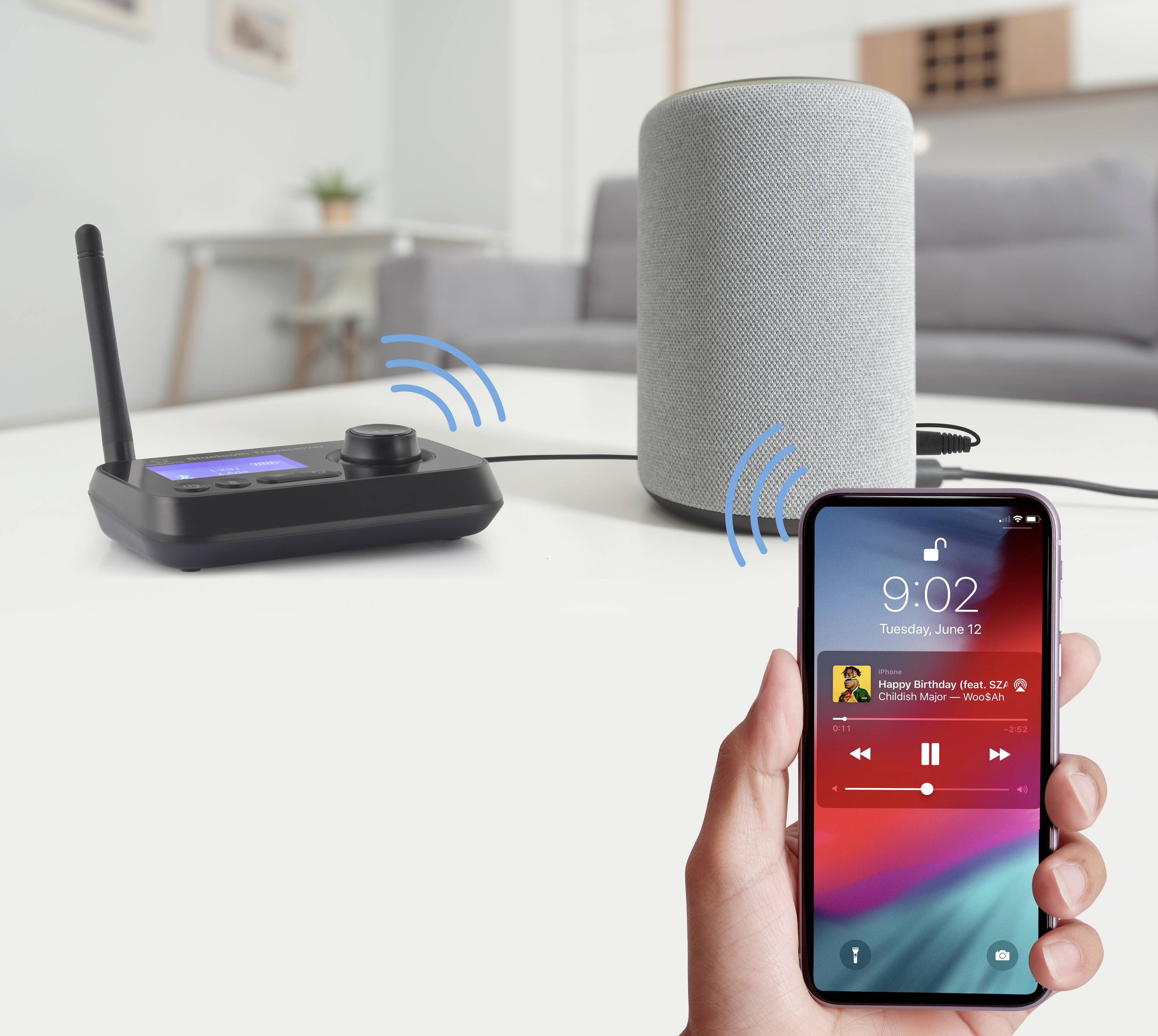 Una persona tiene in mano uno smartphone che mostra una connessione Bluetooth. Sullo sfondo un altoparlante e un ricevitore musicale wireless.
