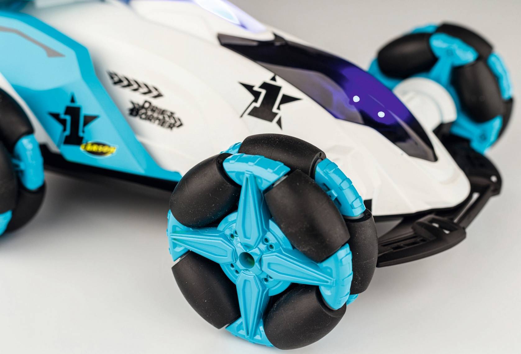 Macchina giocattolo dal design futuristico in blu e bianco. Grandi ruote con elementi blu e neri, adatta per bambini.