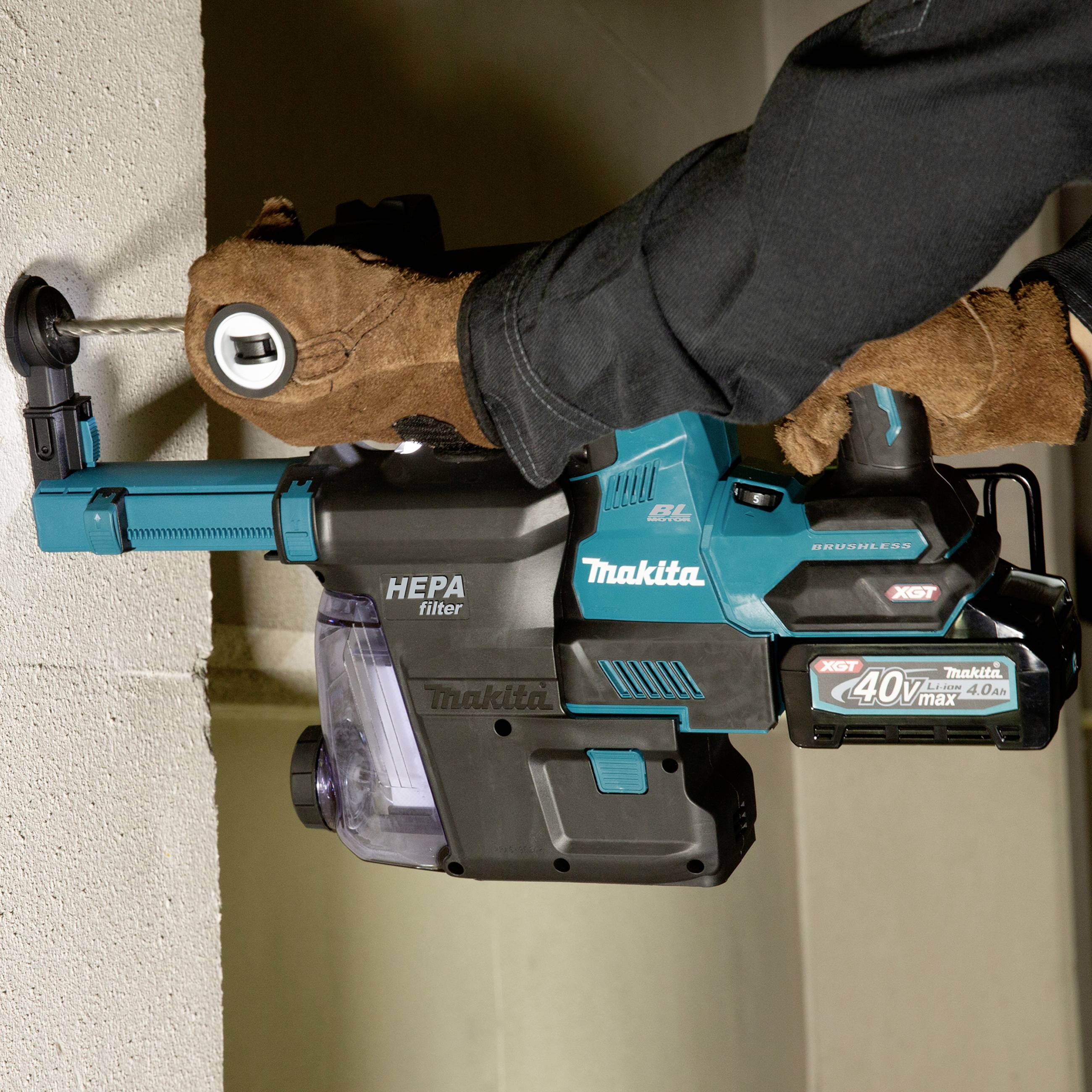 Una persona sta utilizzando un martello demolitore Makita per forare un muro in calcestruzzo. Il trapano ha un accessorio con filtro HEPA.