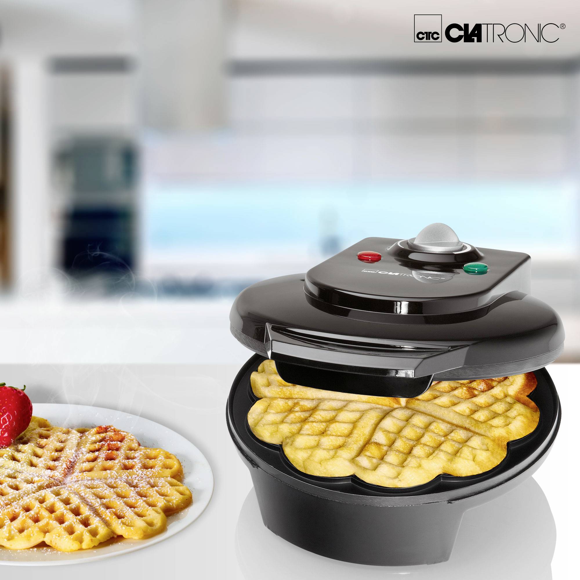 Un ferro per waffle con cialde rotonde su un tavolo. Una waffle già pronta è adagiata accanto, spolverata di zucchero a velo e decorata con fragole.