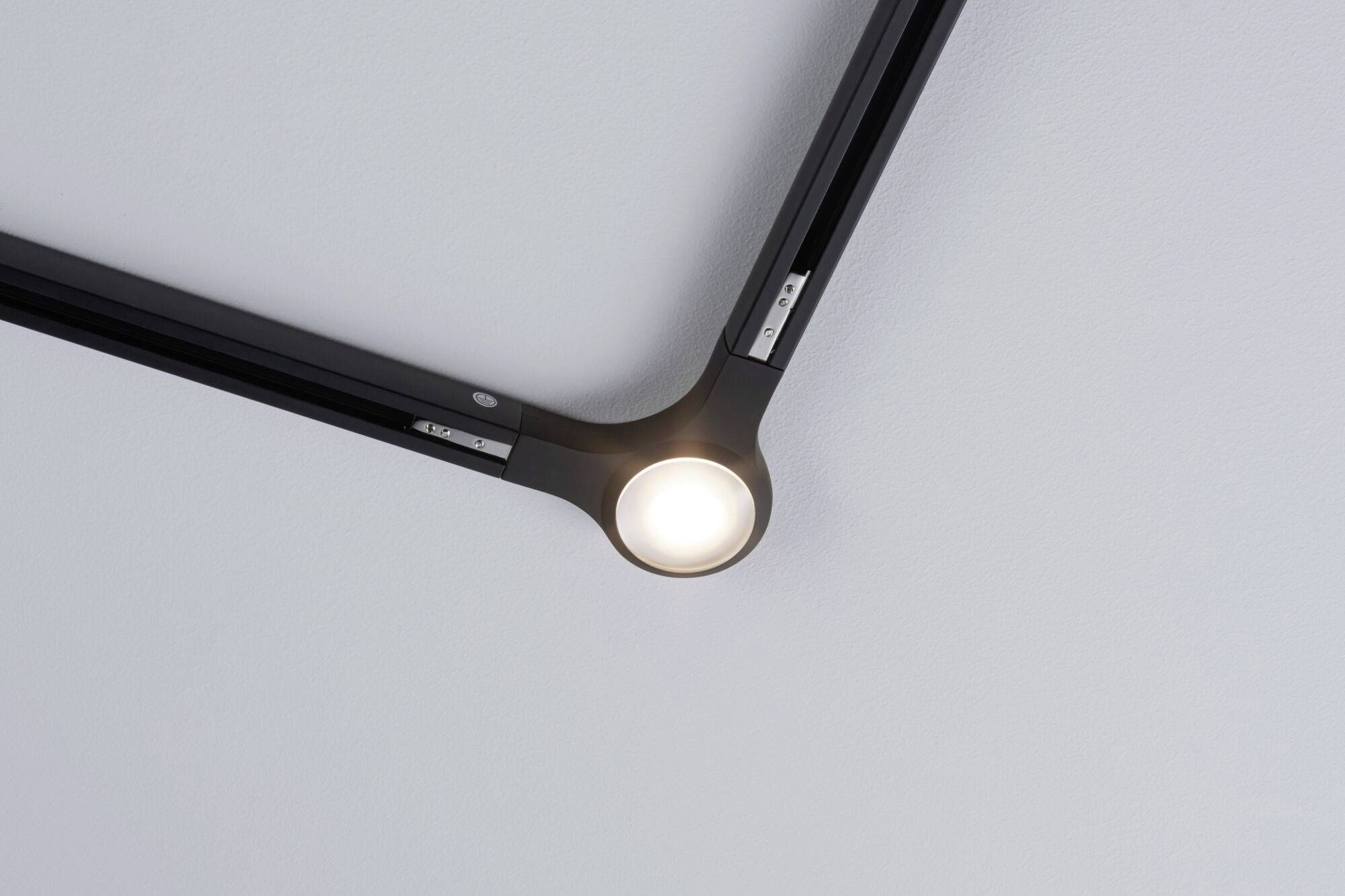 Lampada su un supporto da soffitto nero moderno, illuminata su un soffitto chiaro. Design minimalista, funzionale ed elegante.
