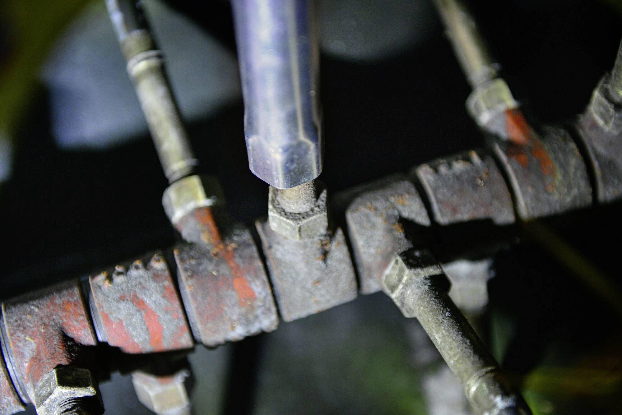 Tubi metallici arrugginiti con giunzioni e raccordi. La superficie è deteriorata, con evidenti tracce di ruggine e usura.
