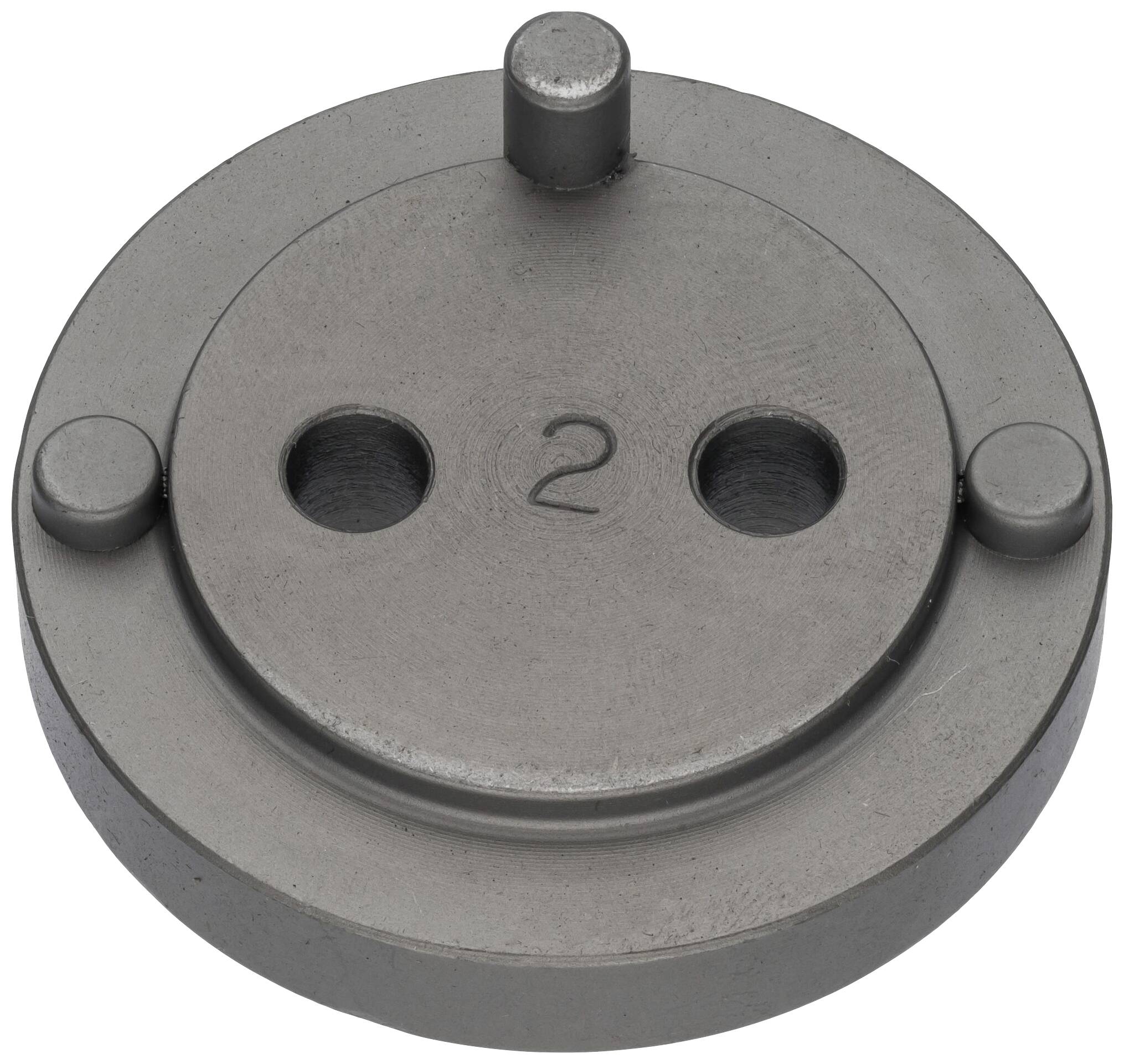 Una piastra rotonda in metallo con tre rilievi, due grandi fori e un numero '2' inciso al centro.