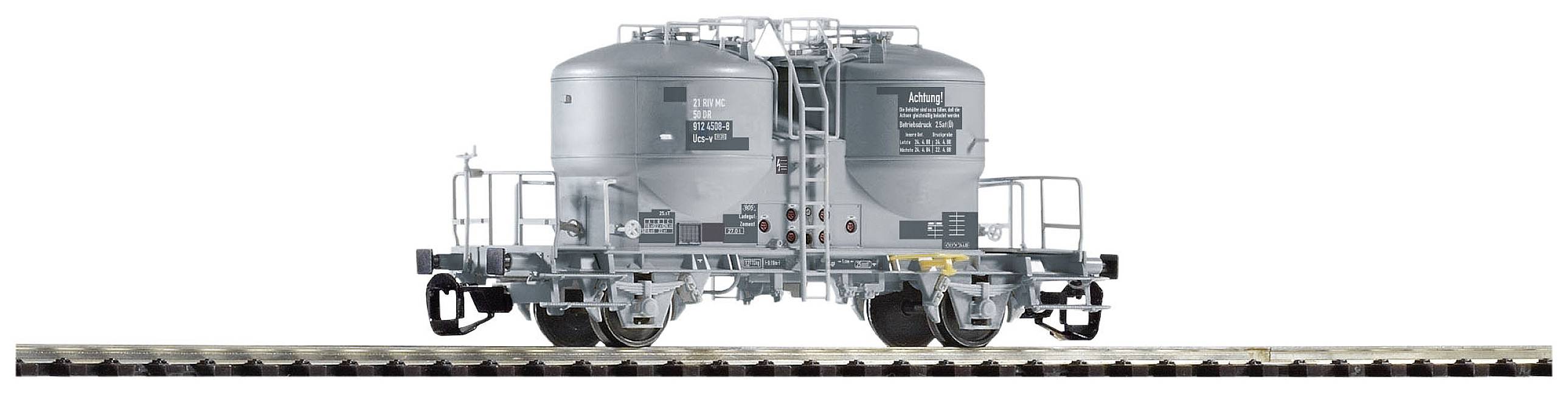 Vagone cisterna ferroviario grigio verniciato su binario, vista laterale. Il vagone ha due grandi serbatoi e numerose etichette.