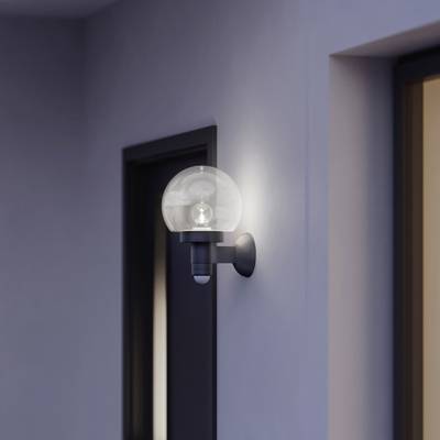 Applique con sfera di vetro montata in un corridoio, su una parete color lavanda. Porta scura sullo sfondo.