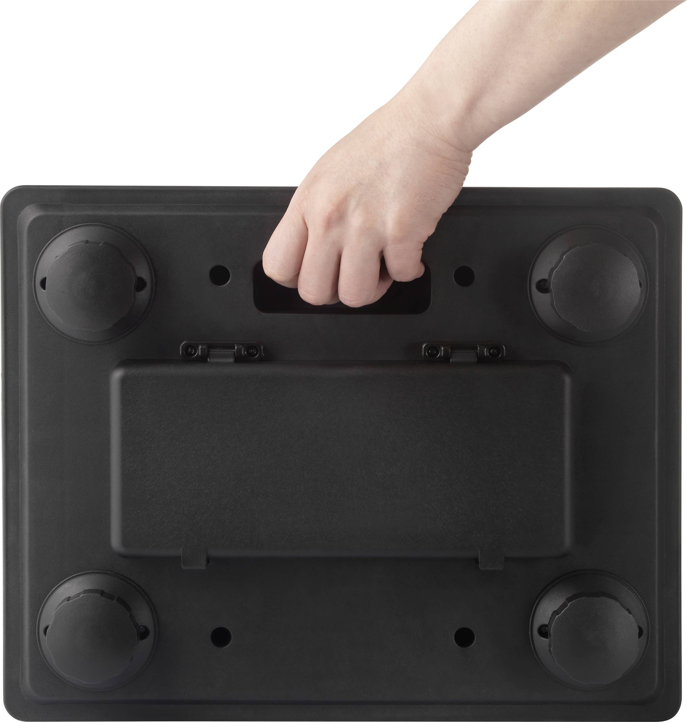 Una mano tiene un manico nero di una valigia dal basso, sono visibili quattro piedini rotondi.