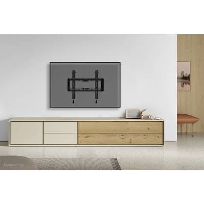 Un soggiorno minimale con un grande televisore montato a parete sopra un moderno mobile credenza in legno.