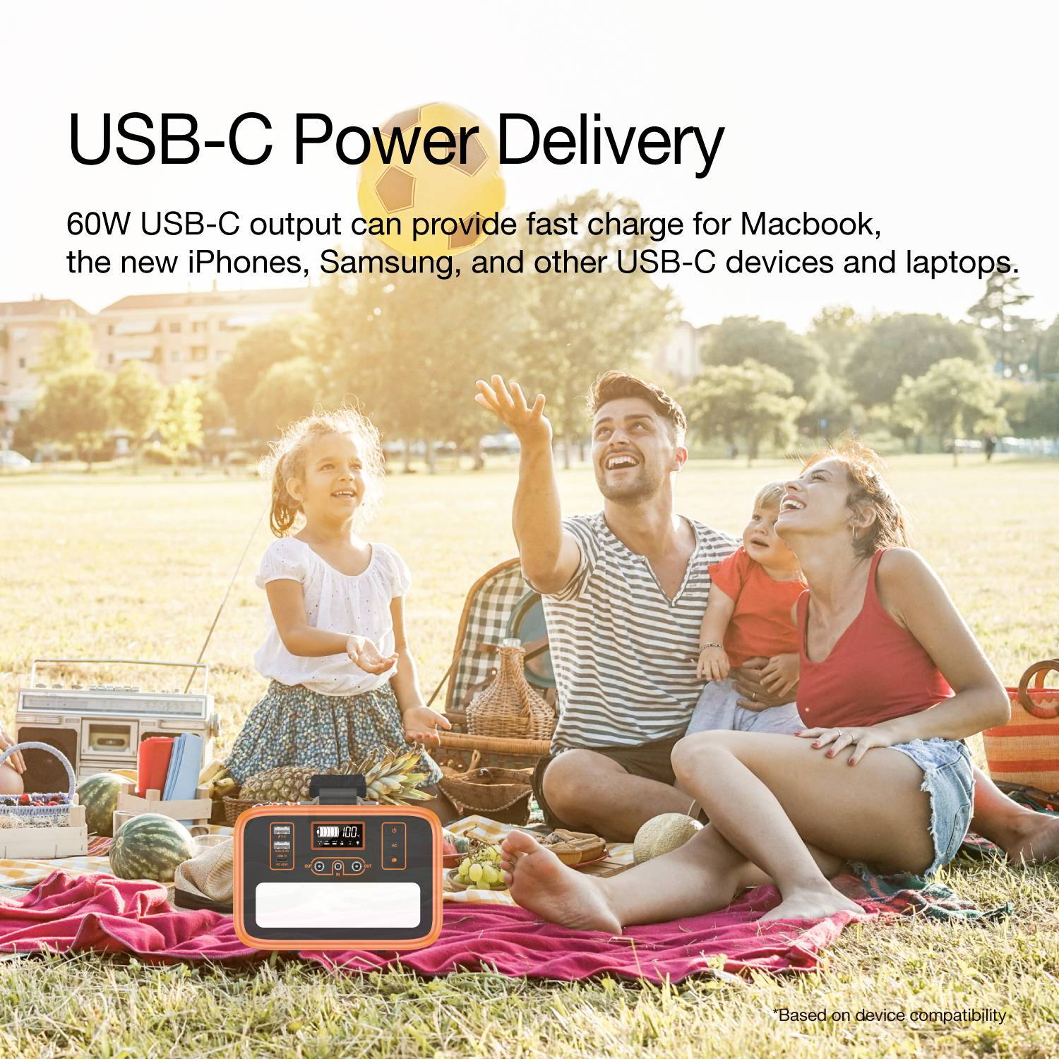 Gruppo di persone sedute su un telo da picnic all'aperto che ridono. In primo piano un caricabatterie portatile USB-C. Testo: 'USB-C Power Delivery'.
