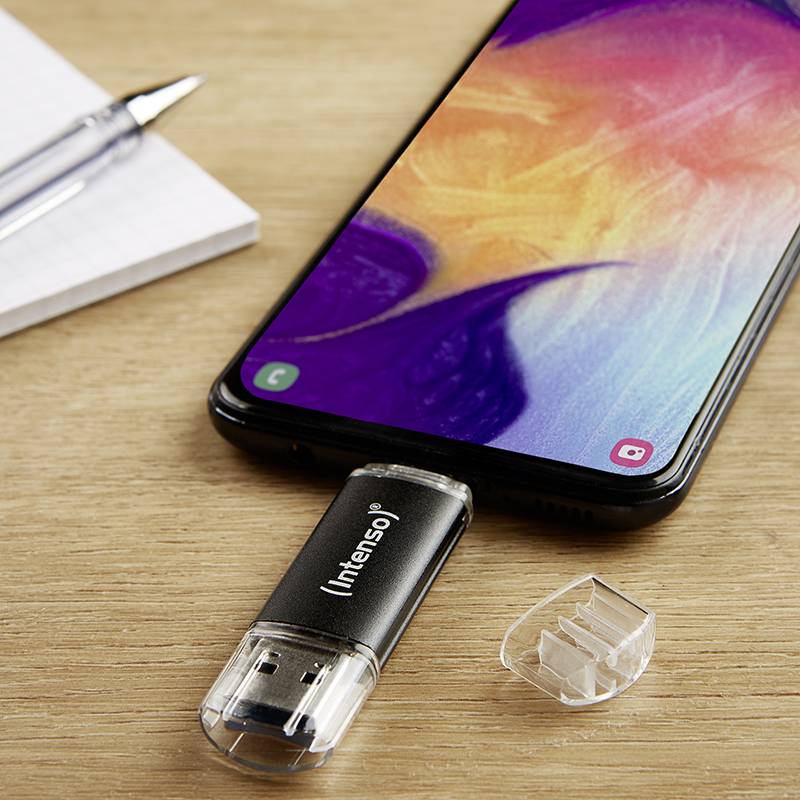 Uno smartphone con schermo attivo mostra una grafica colorata, collegato a una chiavetta USB Intenso. Accanto ci sono un block notes e una penna.