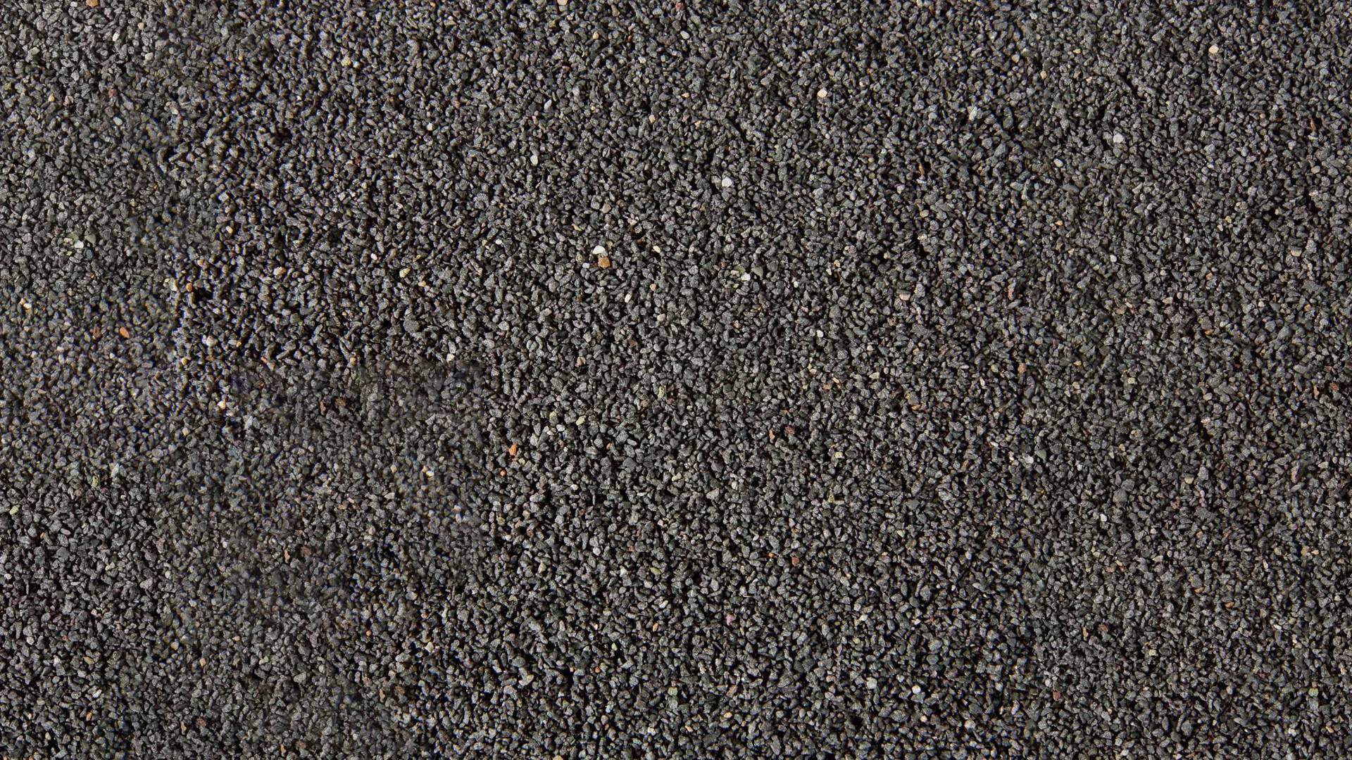 Un primo piano di sabbia nera, distribuita uniformemente. La texture e il colore sono gli elementi principali dell'immagine, senza oggetti visibili.