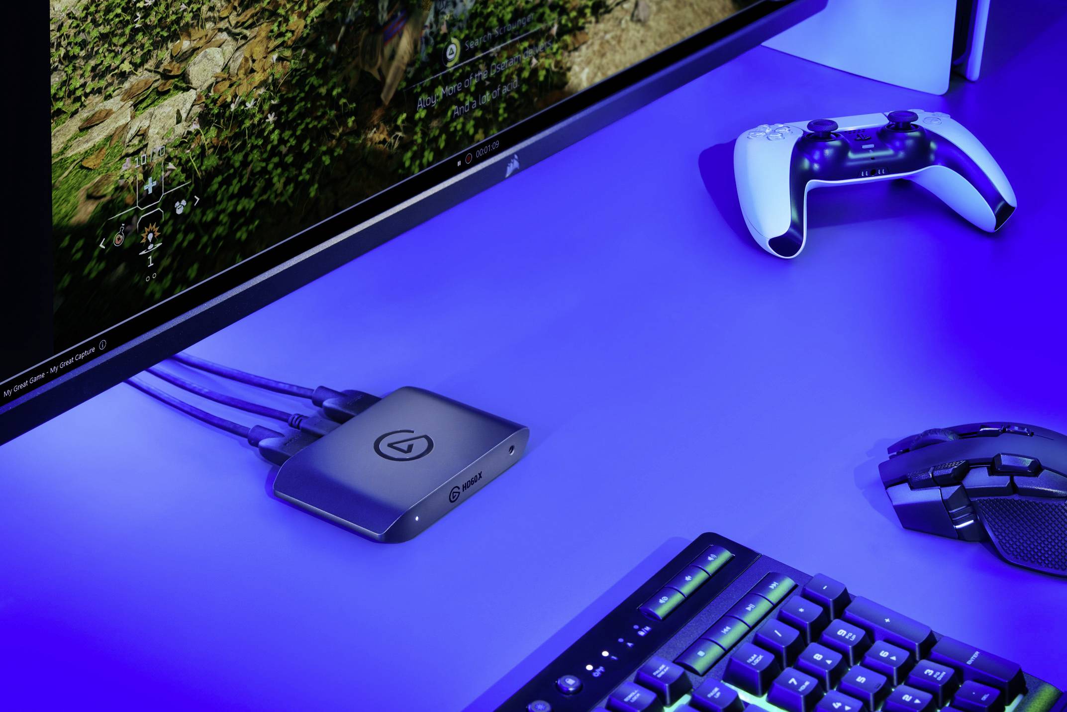 Scrivania da computer con schermo che mostra un videogioco. In primo piano sono visibili un gamepad, una tastiera e un mouse.