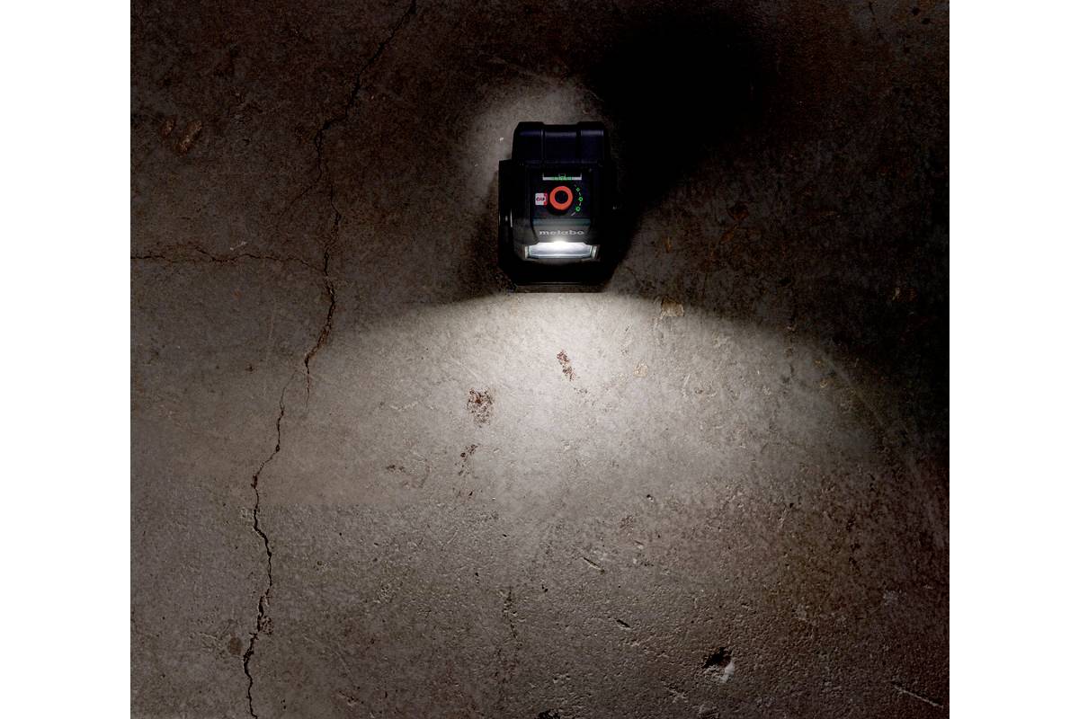 Un dispositivo laser proietta una luce intensa su un pavimento di cemento scuro, illuminando la superficie e creando contrasti.