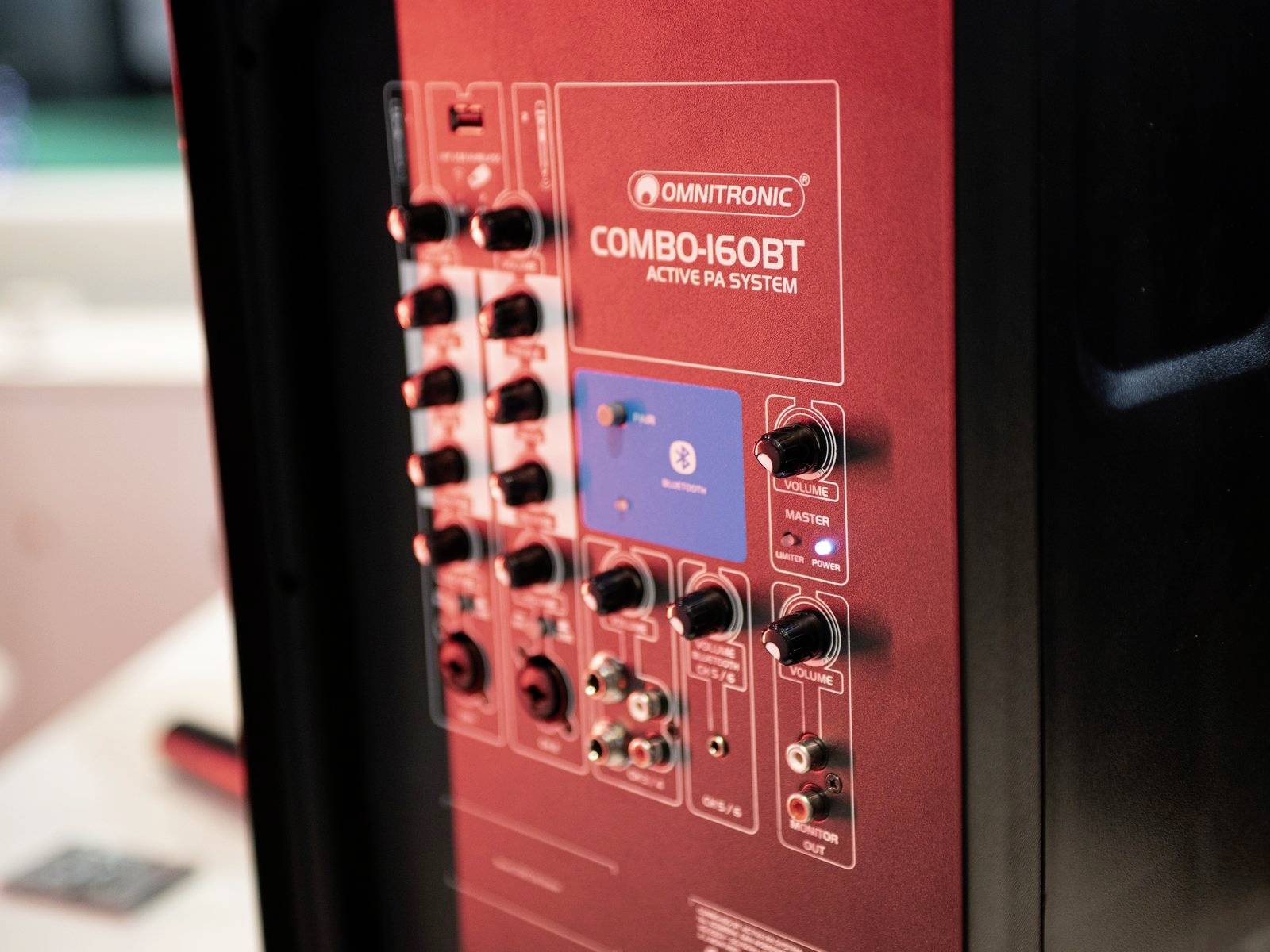 Un retro di un sistema PA Omnitronic Combo-160BT rosso con vari connettori e controlli in un ambiente di studio.