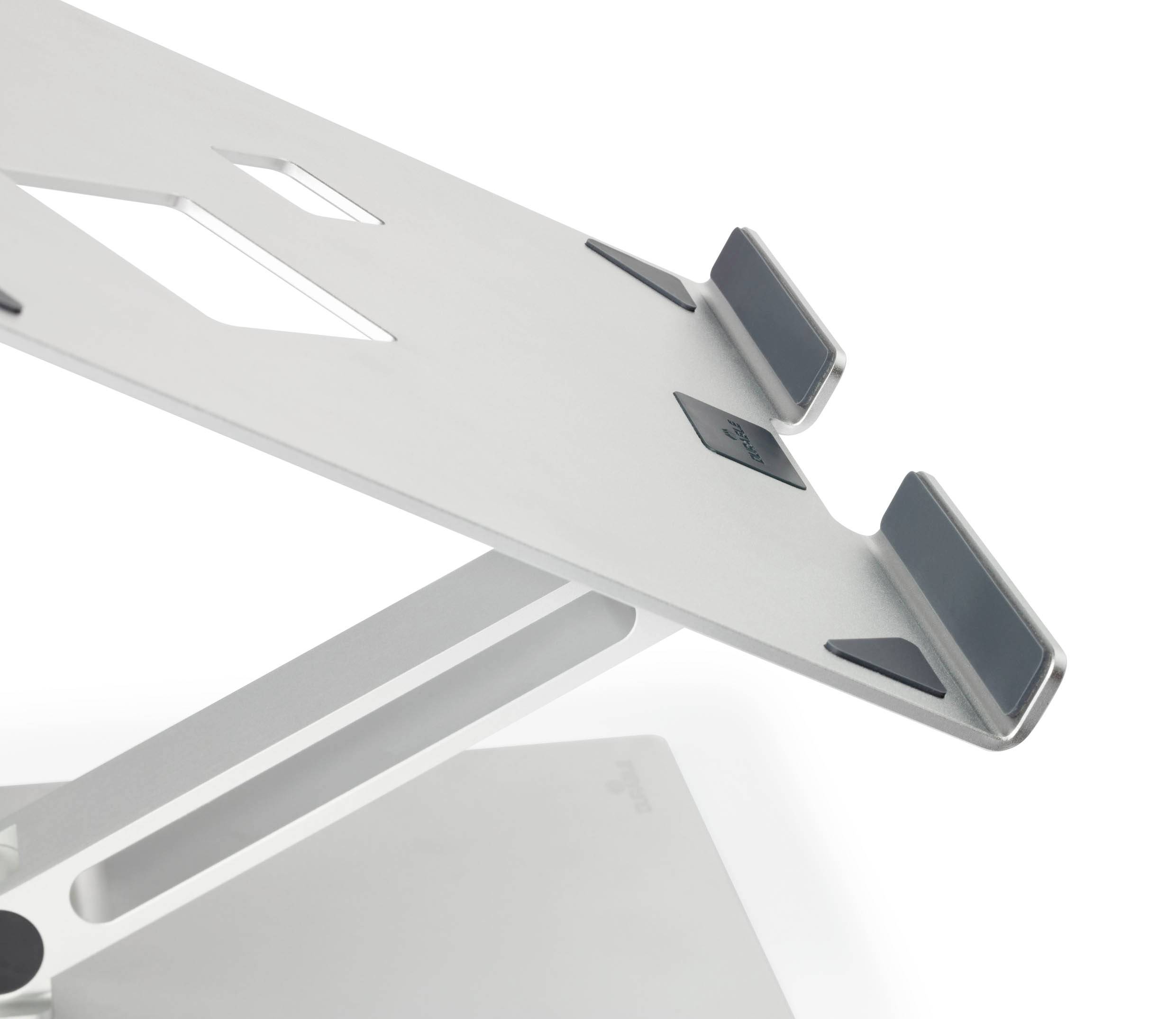 Supporto per laptop argentato in alluminio, ripreso da un'angolazione inclinata. Il supporto ha cuscinetti antiscivolo in gomma agli angoli e una forma snella e moderna.