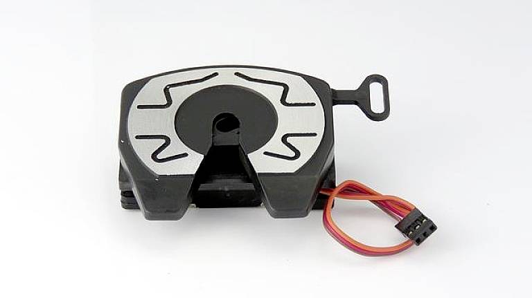 Un componente quadrato nero con linee grigie e un connettore con cavi mostra un design di componente elettronico.