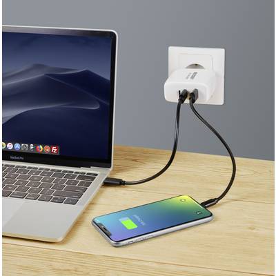 Laptop e smartphone su un tavolo di legno. Entrambi i dispositivi sono collegati a una presa elettrica tramite un caricabatterie. Lo smartphone mostra la batteria verde.