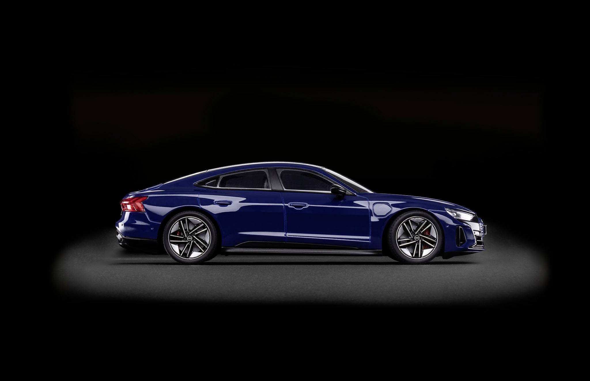 Auto elettrica blu in vista laterale su sfondo nero. Focus sul design aerodinamico e sui cerchi moderni.