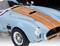 Un'auto sportiva d'epoca blu chiaro con strisce arancioni da corsa. Prese d'aria vistose sul cofano e paraurti cromato.