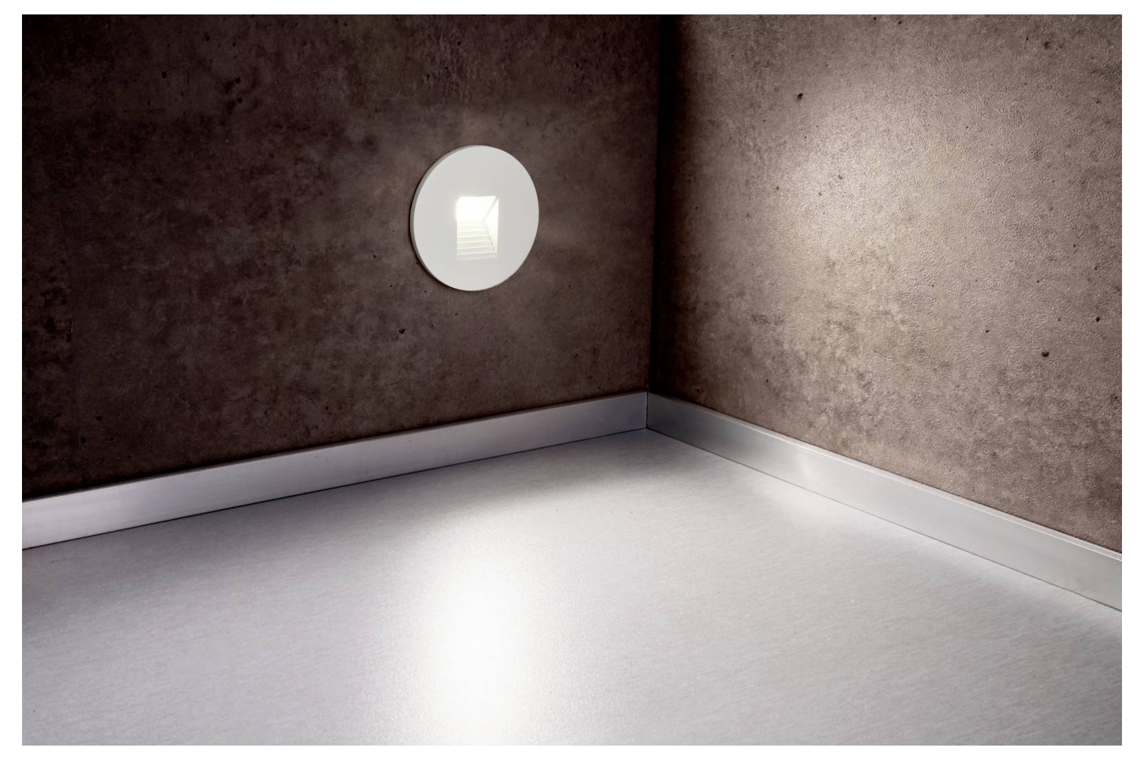 Angolo vuoto di una stanza con una lampada da parete circolare che proietta un fascio luminoso intenso sul pavimento e sulle pareti.