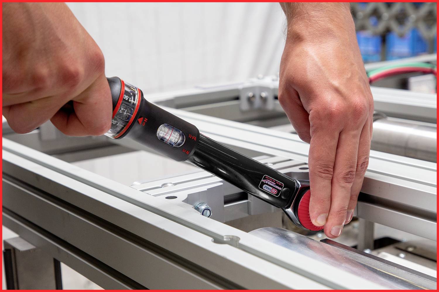 Due mani manovrano un utensile elettronico su una struttura metallica. Lo strumento viene utilizzato per misurare o regolare.