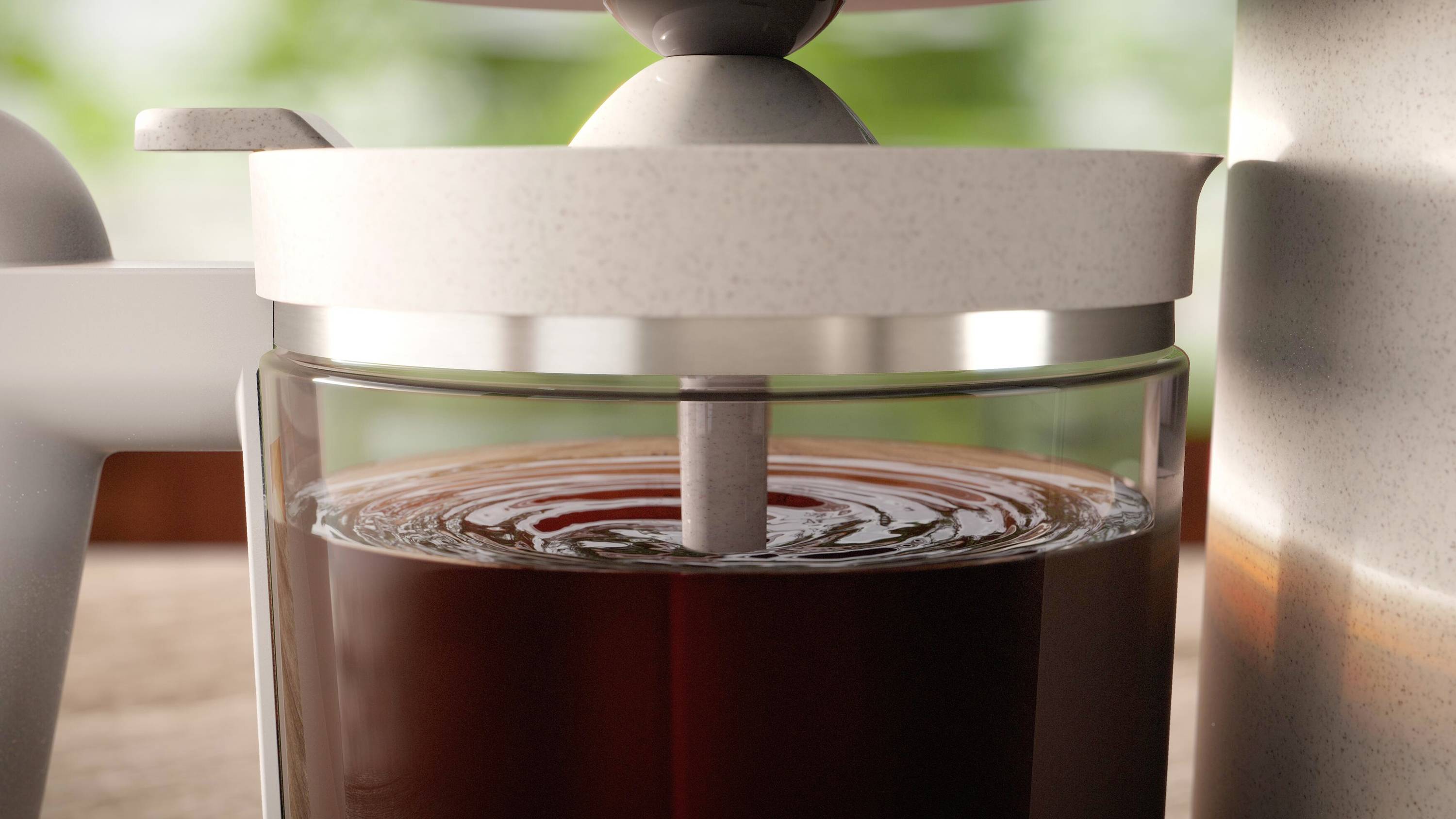 Primo piano di una caffettiera a stantuffo con caffè appena preparato che viene filtrato gradualmente verso il basso.