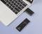 Un laptop con un telecomando nero collegato; accanto c'è una chiavetta USB. Il telecomando ha tasti direzionali.