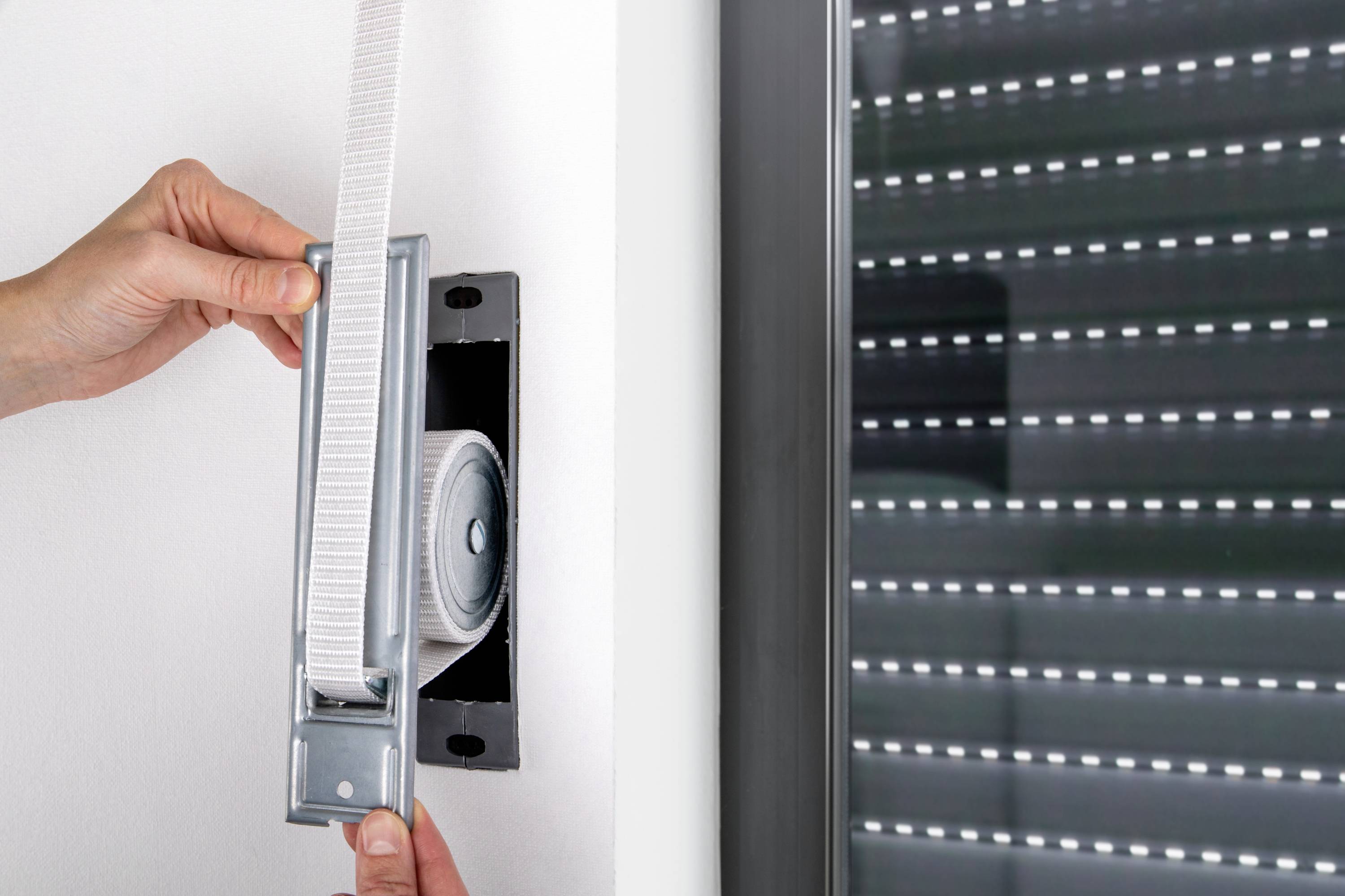 Una persona ripara la cinghia dell'avvolgibile