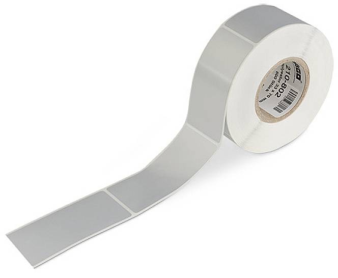 Rotolo di etichette argentate, rettangolari, affiancate su un rullo, con un estratto parziale visibile, su sfondo bianco.