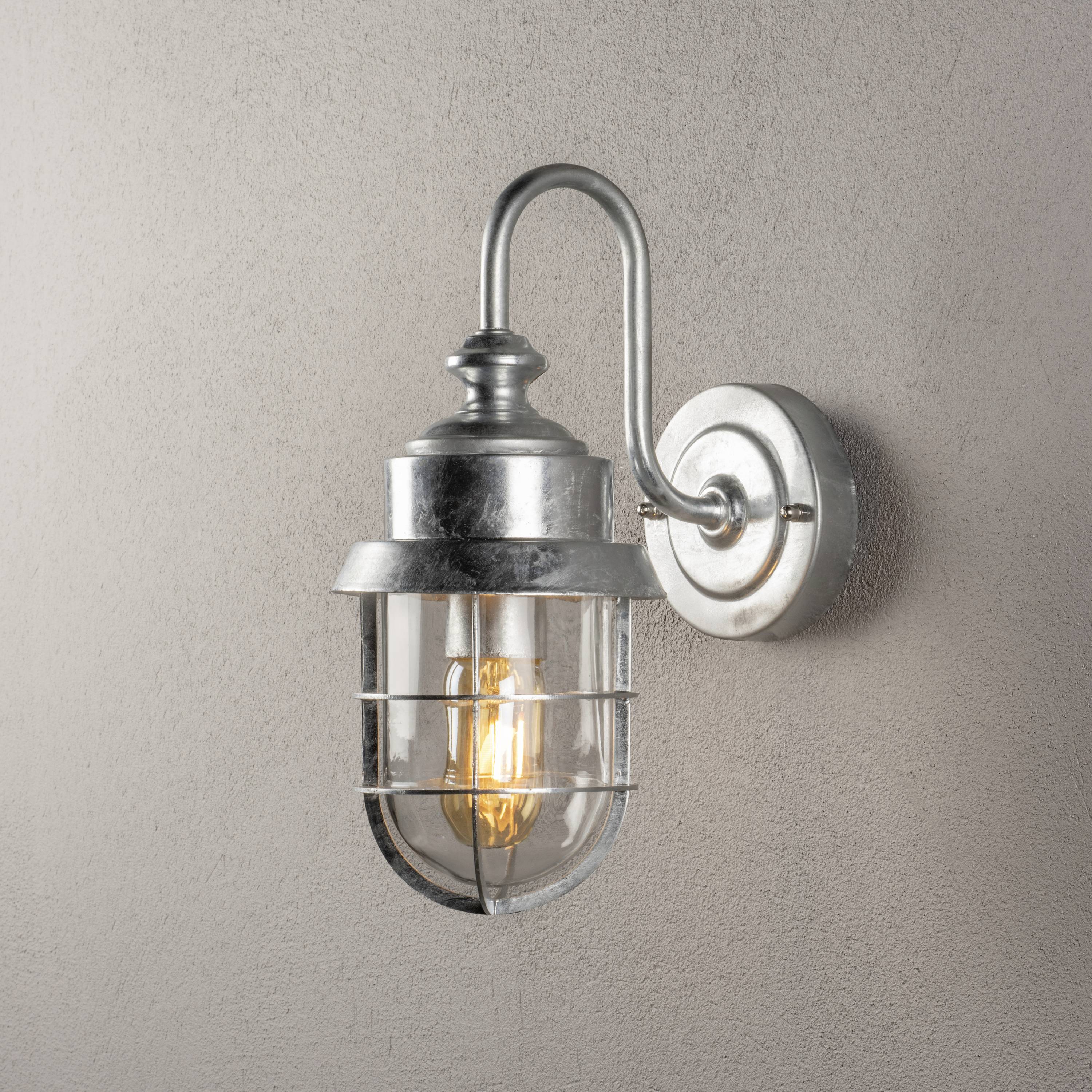 Applique in stile vintage con cornice in metallo e lampadina che emana una luce calda.