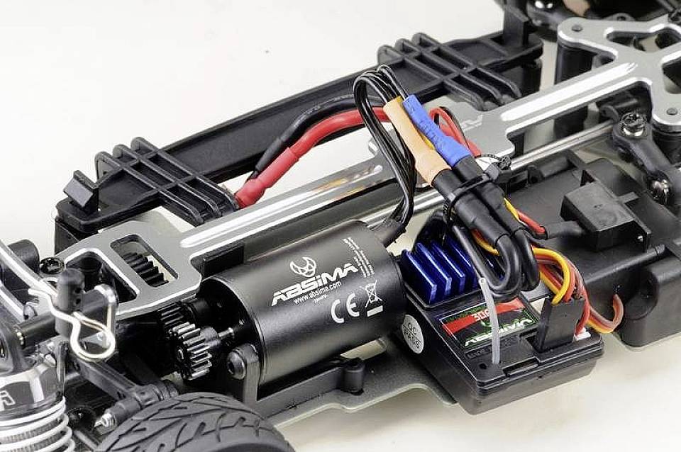 Primo piano del telaio di un modellino di auto radiocomandata. Sono visibili il motore elettrico, il cablaggio e l'elettronica di controllo su un telaio metallico.