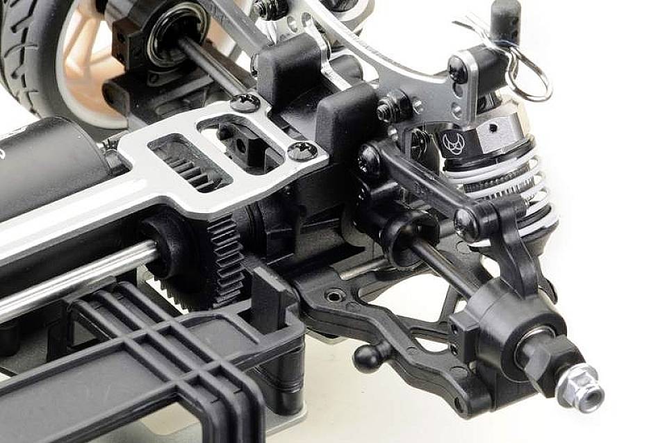 Primo piano di un telaio di un'auto radiocomandata con dettagli del sistema di sospensione e ammortizzazione. Focus sulle componenti meccaniche.