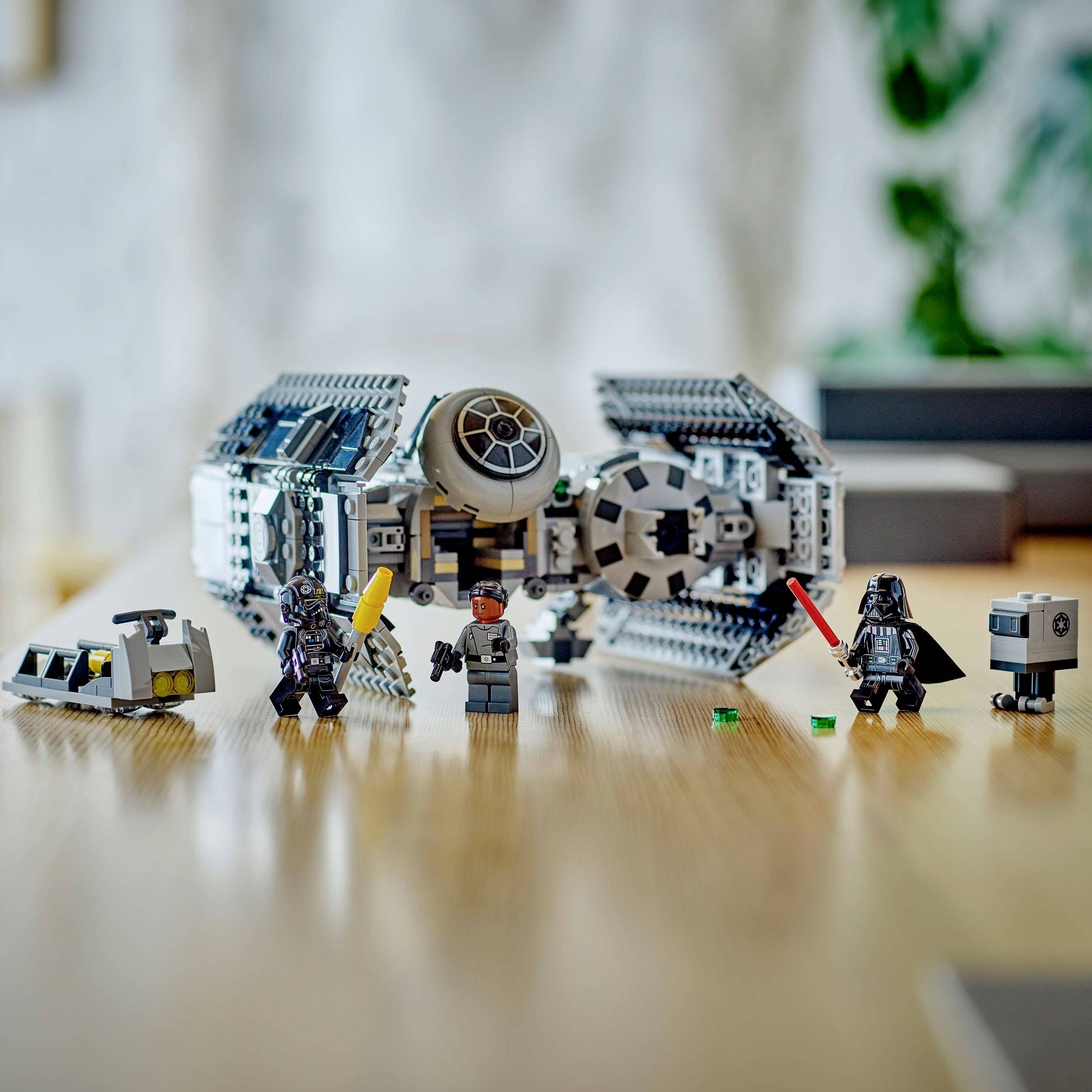 Un modello LEGO Star Wars raffigura una navicella spaziale con quattro figure, tra cui un personaggio vestito di nero e un robot su un tavolo.